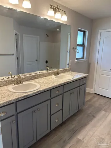 a bathroom with a granite countertop double vanity sink and a mirror