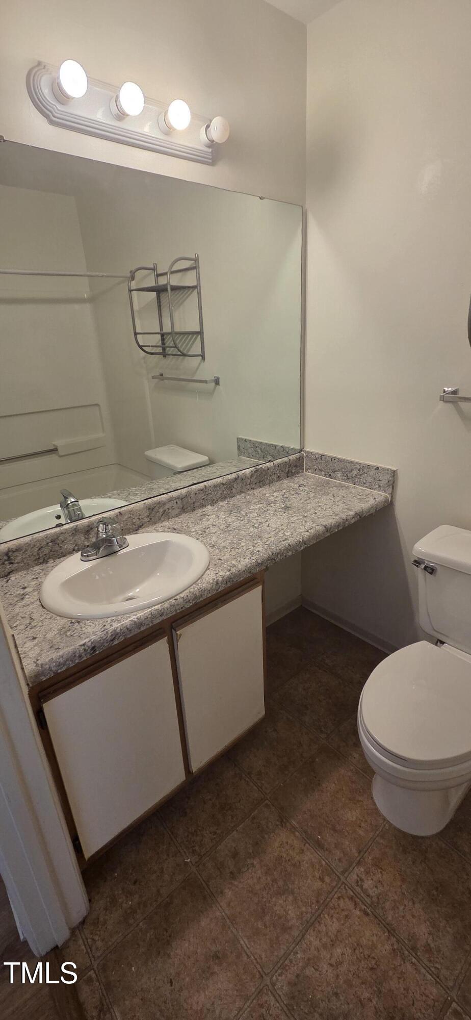 1401 Collegiate Circle, Unit 104 Raleigh, NC 27606 - Photo 15 of 29 a bathroom with a granite countertop sink a toilet and a mirror