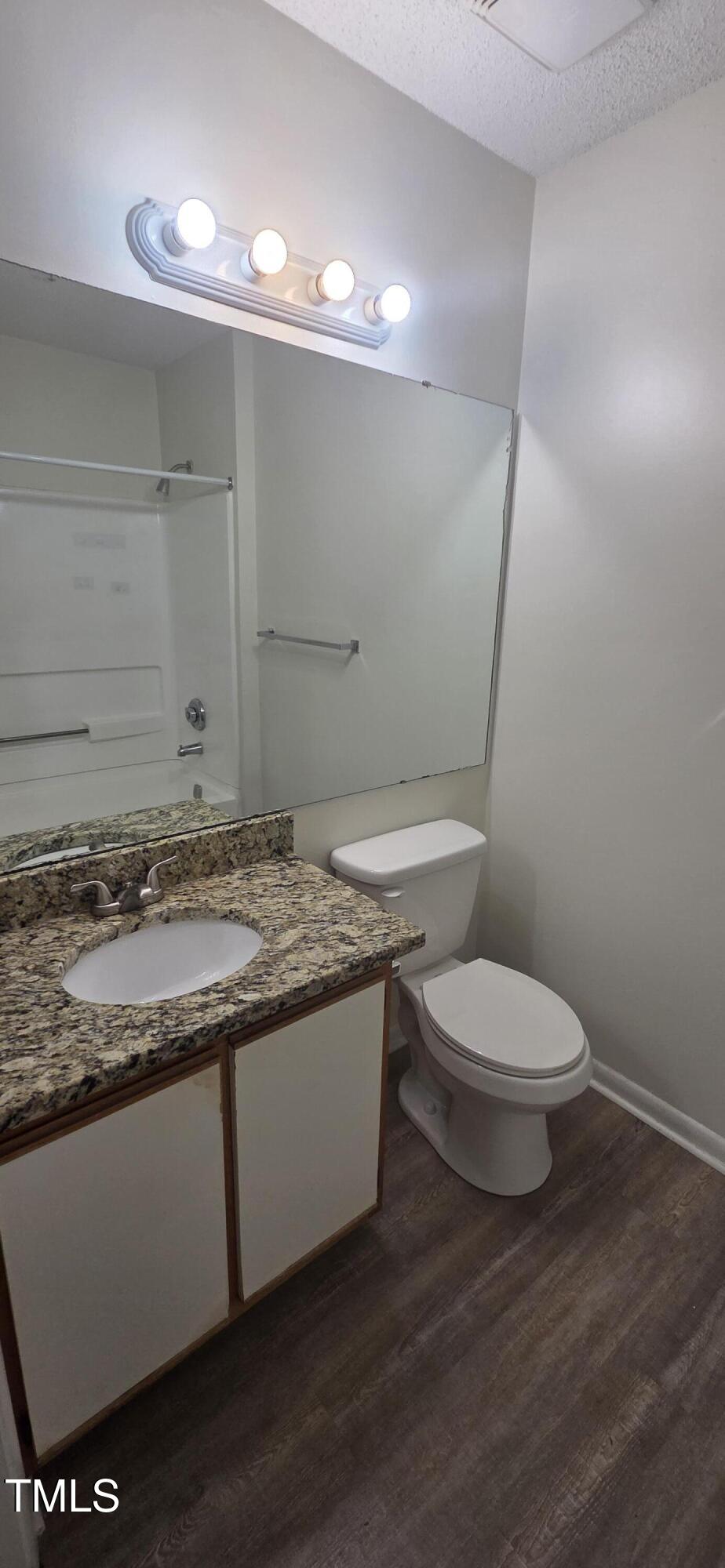 1401 Collegiate Circle, Unit 104 Raleigh, NC 27606 - Photo 22 of 29 a bathroom with a granite countertop toilet and a sink