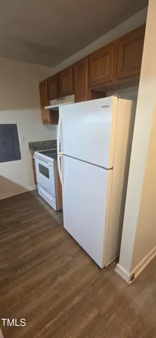 a view of a refrigerator in kitchen and an empty room