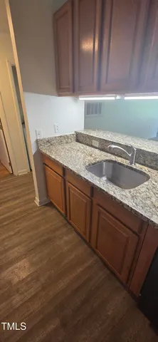 a view of a kitchen with kitchen island a sink wooden floor and a counter top space