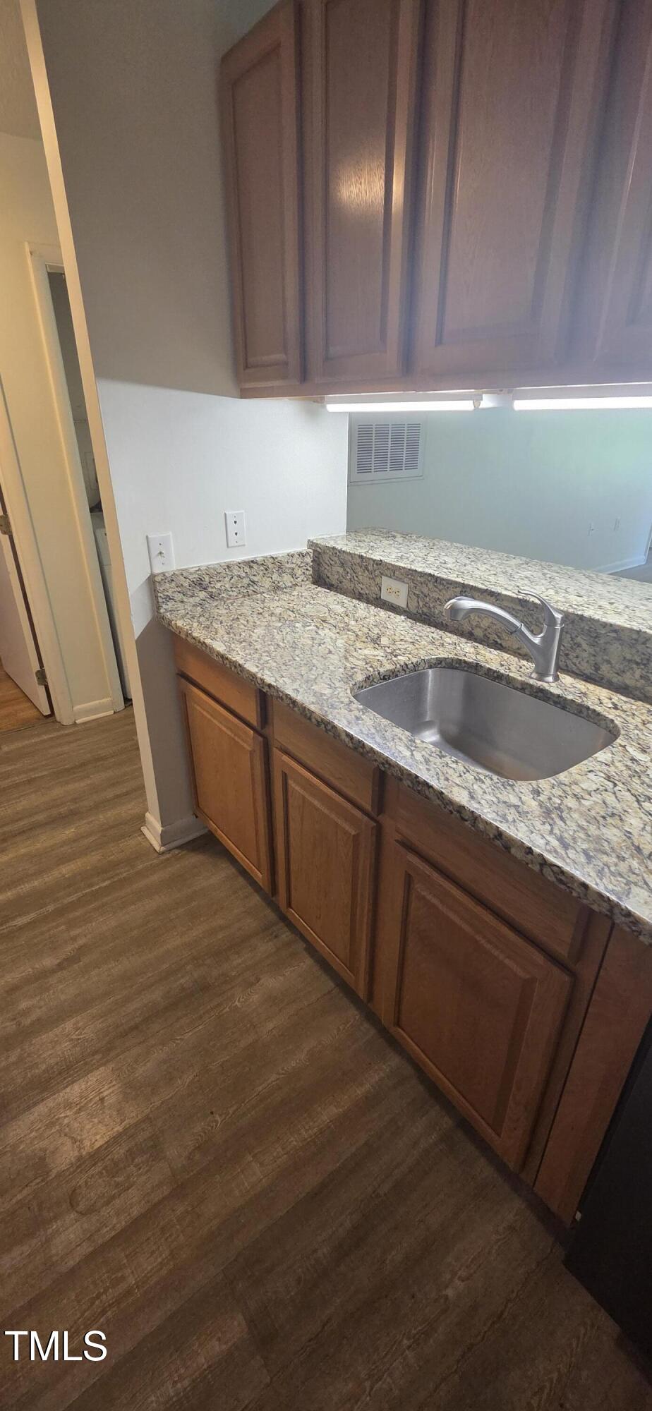 1401 Collegiate Circle, Unit 104 Raleigh, NC 27606 - Photo 10 of 29 a view of a kitchen with kitchen island a sink wooden floor and a counter top space