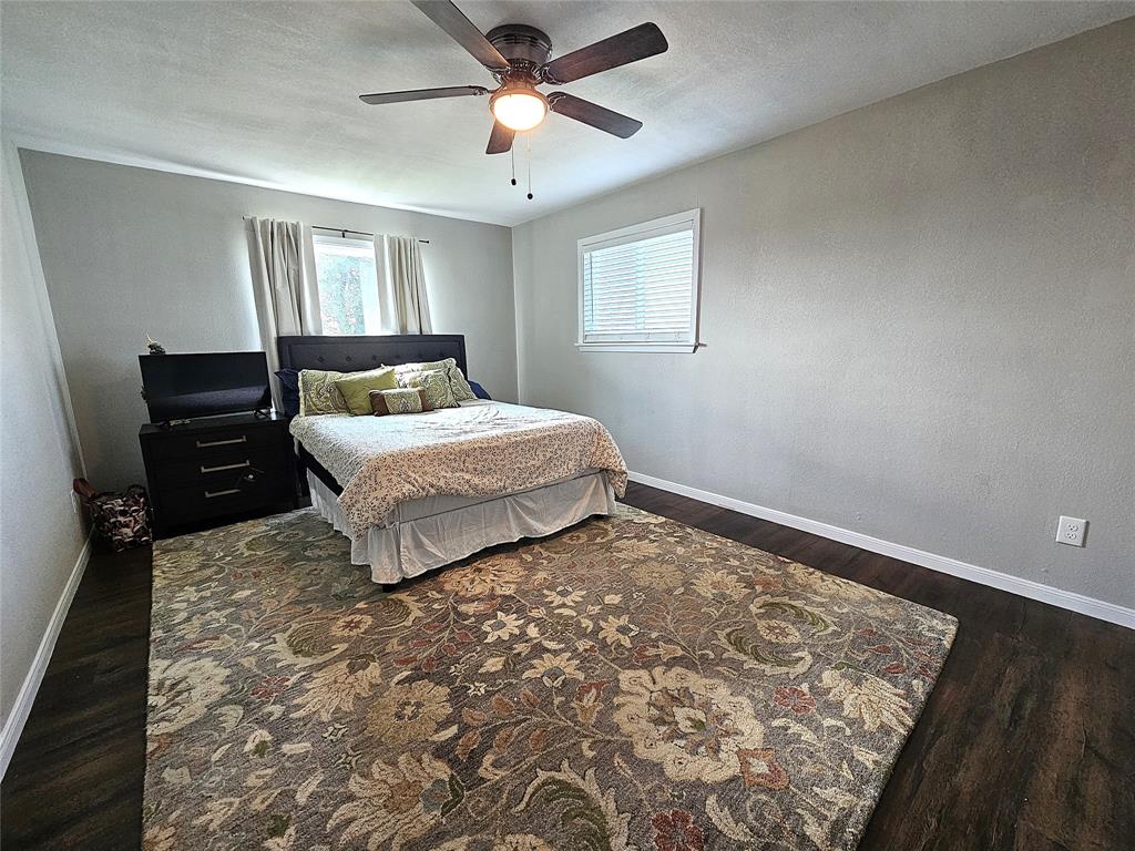 1205 West Trinity Street Groesbeck, TX 76642 - Photo 14 of 28 a bedroom with a bed and wooden floor