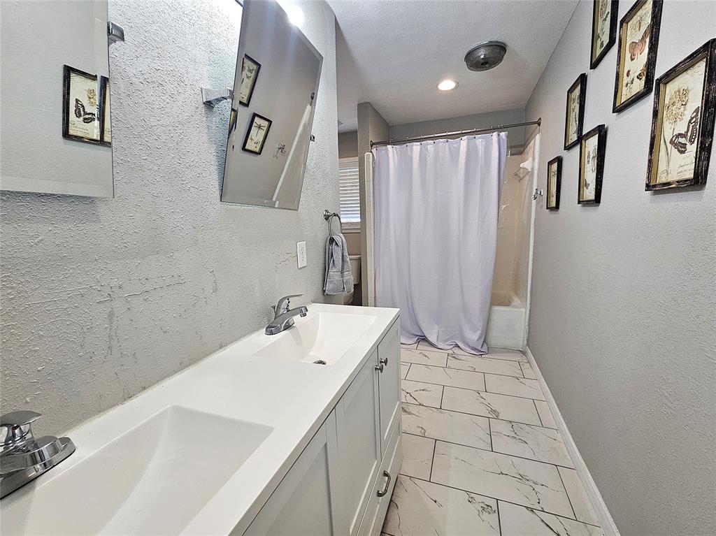 1205 West Trinity Street Groesbeck, TX 76642 - Photo 16 of 28 a bathroom with a sink a mirror and a shower