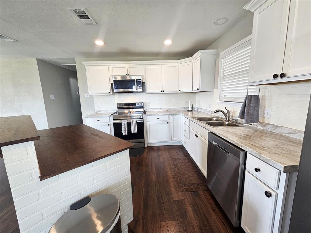 1205 West Trinity Street Groesbeck, TX 76642 - Photo 7 of 28 a kitchen with stainless steel appliances granite countertop a white cabinets a sink a stove a refrigerator and island
