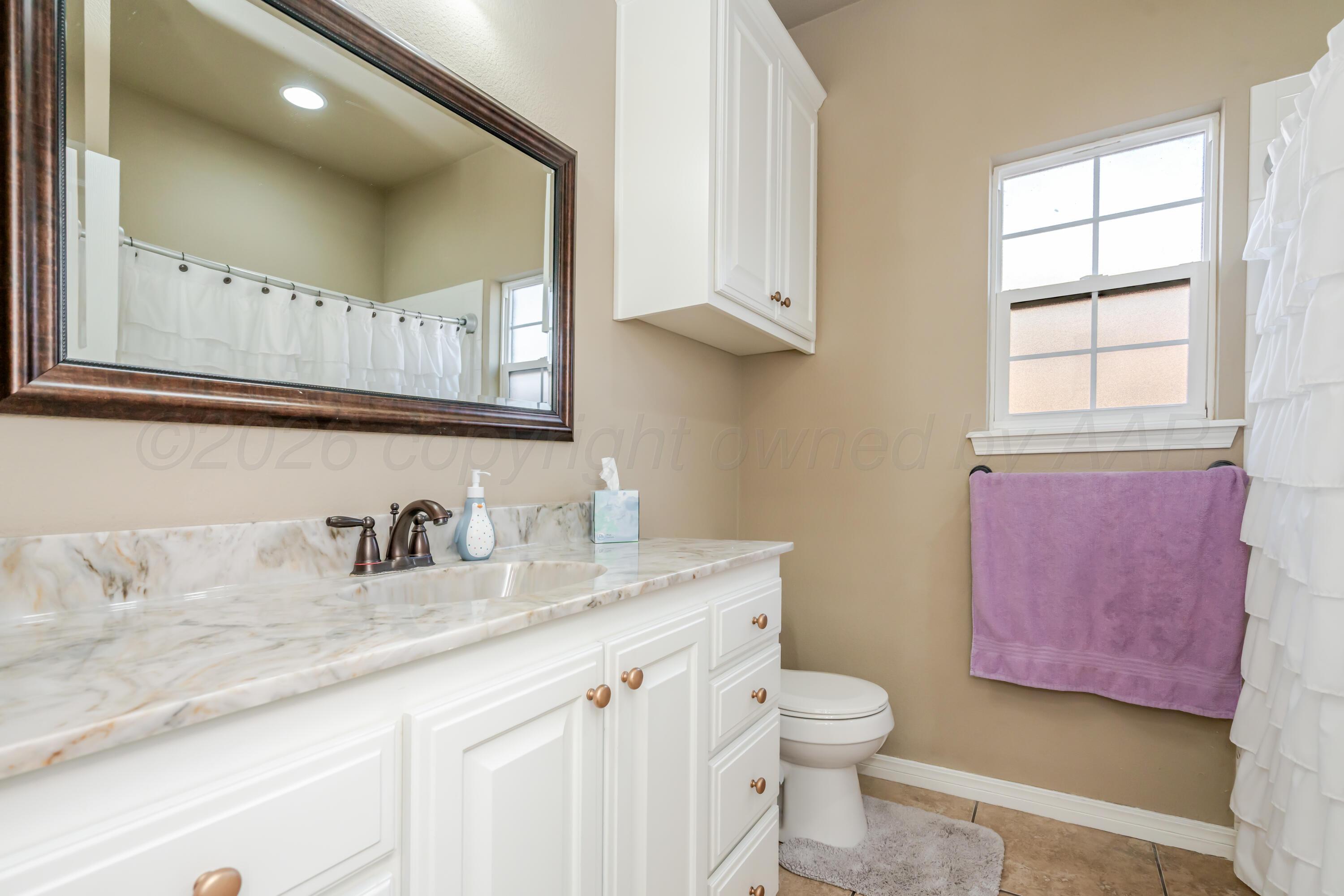 6814 Tivis Street Amarillo, TX 79119 - Photo 17 of 37 a bathroom with a granite countertop toilet sink and mirror