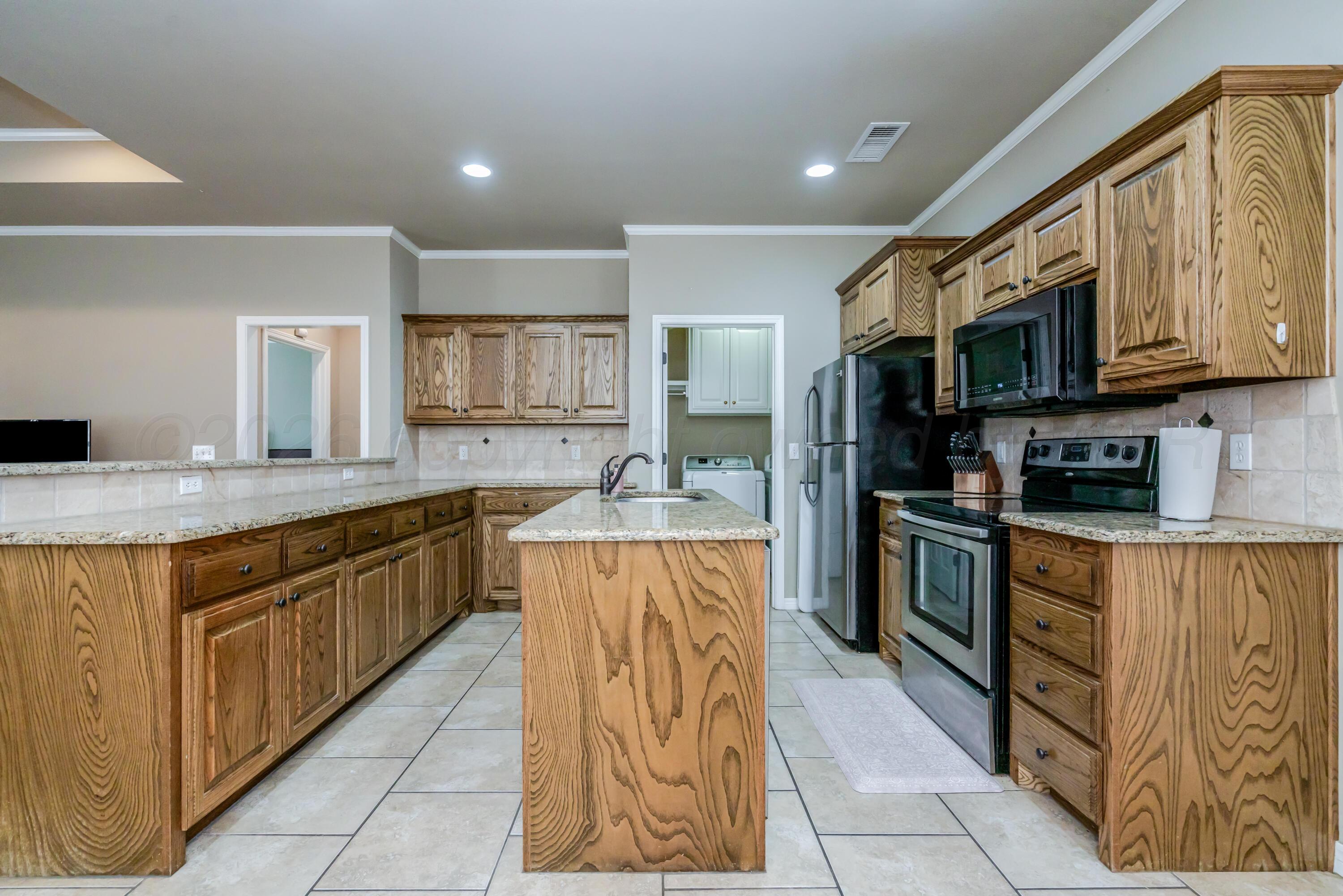 6814 Tivis Street Amarillo, TX 79119 - Photo 7 of 37 a kitchen with stainless steel appliances granite countertop a stove top oven a sink dishwasher and a refrigerator with wooden cabinets