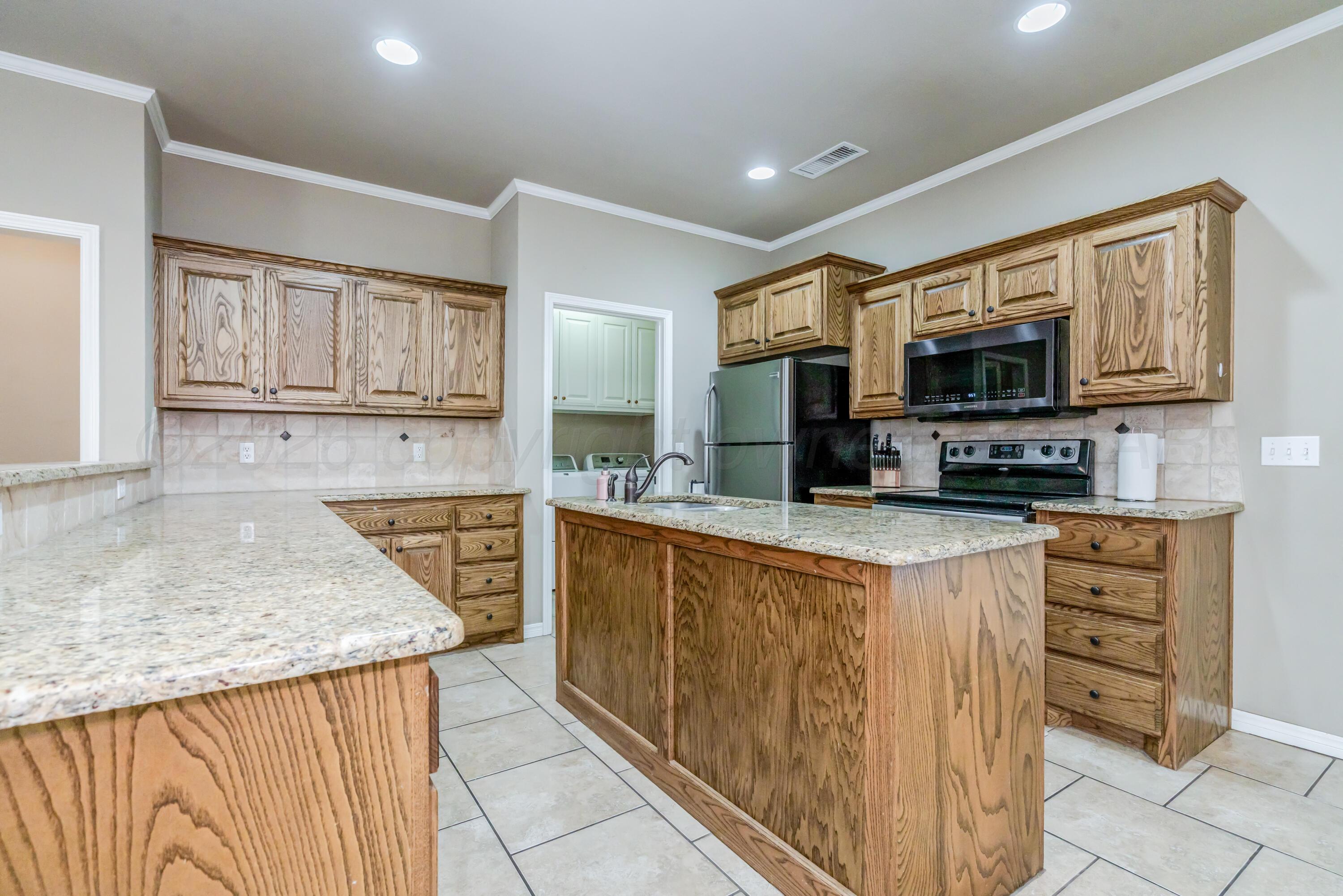 6814 Tivis Street Amarillo, TX 79119 - Photo 9 of 37 a kitchen with stainless steel appliances granite countertop a stove top oven a sink a microwave and a refrigerator
