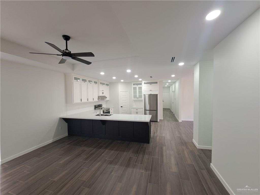 708 East 3rd Avenue Elsa, TX 78543 - Photo 11 of 33 Kitchen with stainless steel refrigerator, a peninsula, a sink, dark wood-type flooring, and baseboards