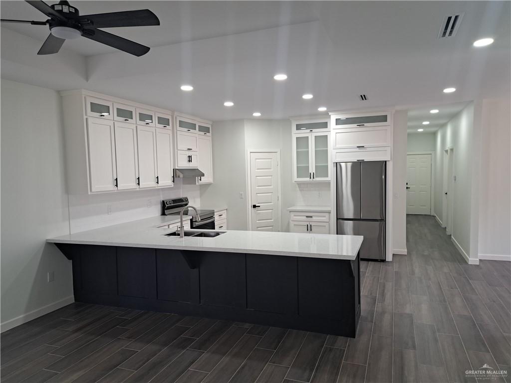 708 East 3rd Avenue Elsa, TX 78543 - Photo 12 of 33 Kitchen with stainless steel appliances, a peninsula, dark wood-style floors, recessed lighting, and baseboards