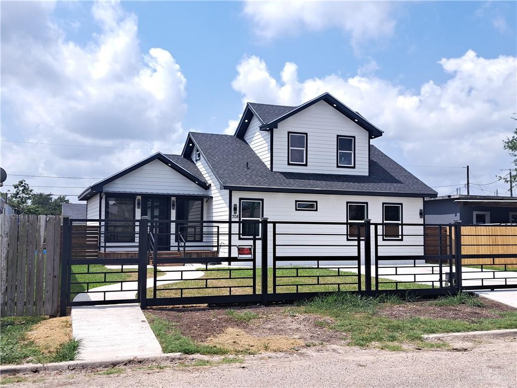 708 East 3rd Avenue Elsa, TX 78543 - Photo 2 of 33 View of front facade with a gate, a sunroom, a shingled roof, and a fenced front yard