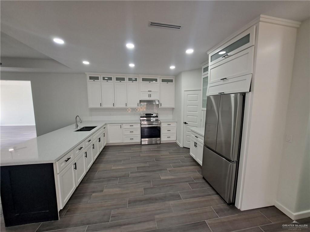 708 East 3rd Avenue Elsa, TX 78543 - Photo 24 of 33 Kitchen featuring appliances with stainless steel finishes, a sink, wood tiled floors, tasteful backsplash, and under cabinet range hood