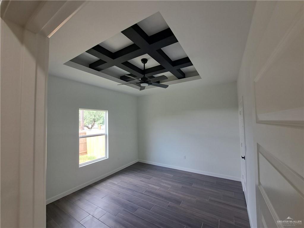 708 East 3rd Avenue Elsa, TX 78543 - Photo 26 of 33 Empty room with coffered ceiling, ceiling fan, beam ceiling, baseboards, and dark wood finished floors
