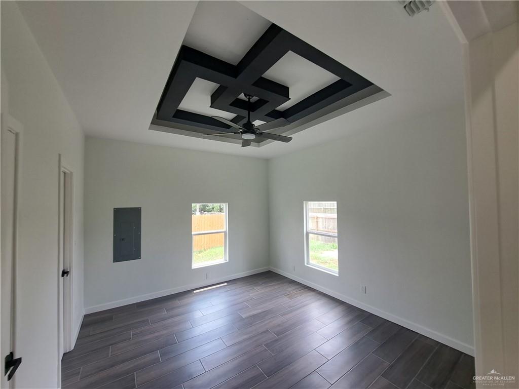 708 East 3rd Avenue Elsa, TX 78543 - Photo 28 of 33 Spare room featuring electric panel, coffered ceiling, ceiling fan, baseboards, and dark wood-style flooring