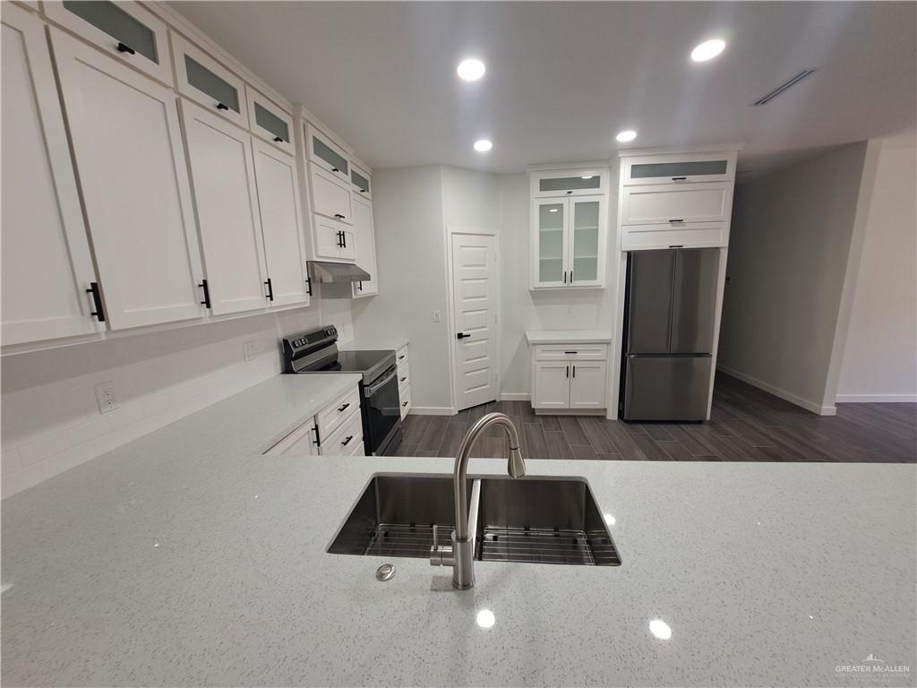 708 East 3rd Avenue Elsa, TX 78543 - Photo 32 of 33 Kitchen with stainless steel refrigerator, range with electric stovetop, a sink, light stone counters, and baseboards