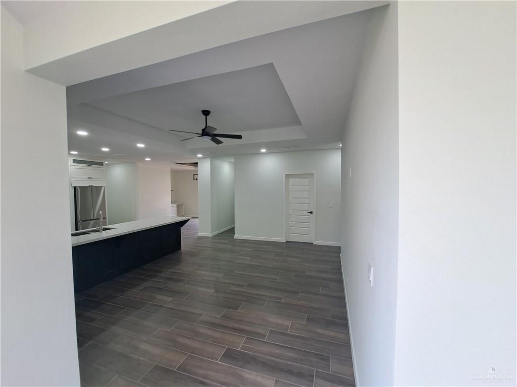 708 East 3rd Avenue Elsa, TX 78543 - Photo 9 of 33 Unfurnished living room with recessed lighting, a ceiling fan, baseboards, wood finish floors, and a tray ceiling