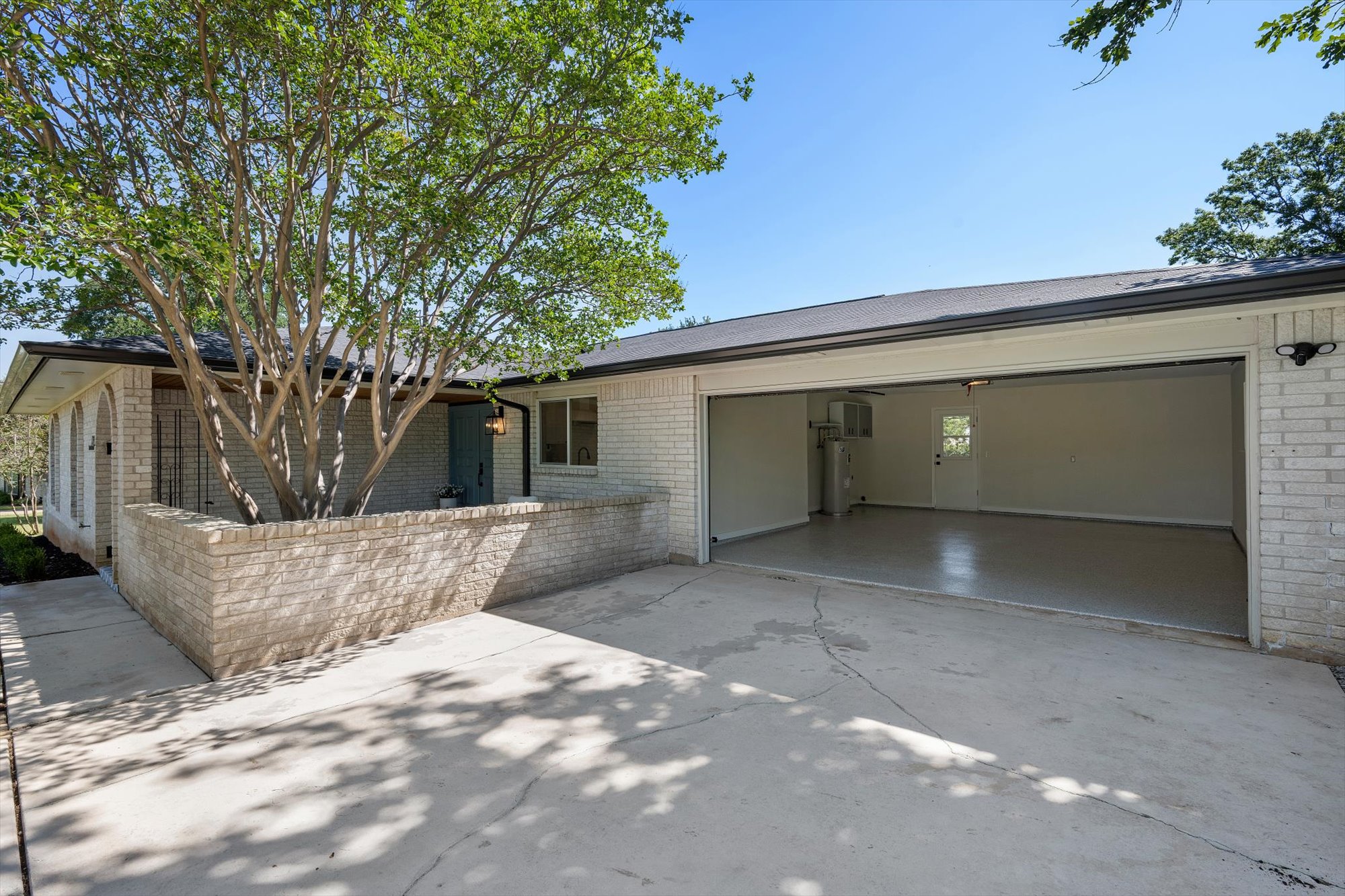 109 Woodland Road Georgetown, TX 78628 - Photo 11 of 40 A well-maintained white brick exterior home features an open garage and mature landscaping for appealing curb appeal.
