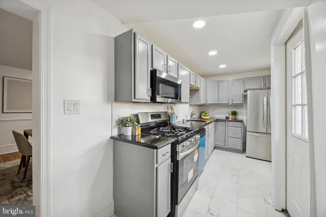 a kitchen with stainless steel appliances granite countertop a stove top oven a sink and a refrigerator