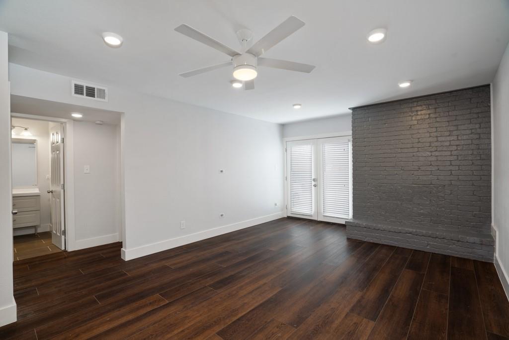 909 Reinli Street, Unit 144 Austin, TX 78751 - Photo 8 of 19 Empty room with dark wood-type flooring, recessed lighting, ceiling fan, brick wall, and french doors