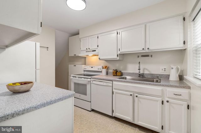 a kitchen with white cabinets and sink