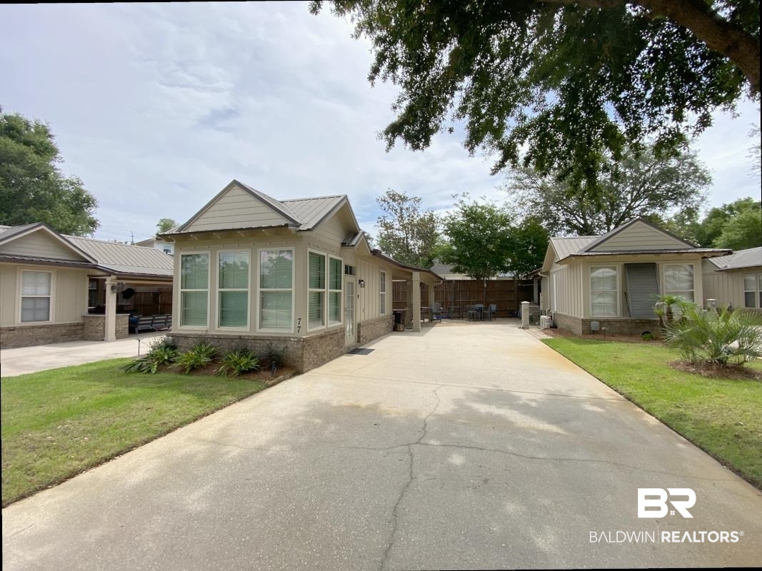 28888 Canal Road, Unit 77 Orange Beach, AL 36561 - Photo 1 of 23 Exterior of a property featuring multiple structures with light-colored siding, stone veneer accents, and gray metal roofs