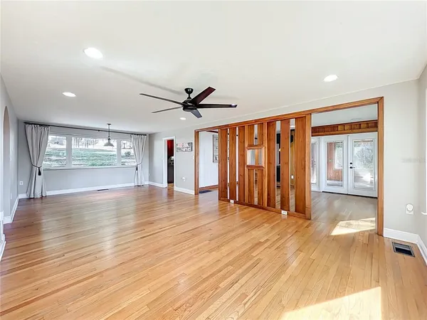 a view of an empty room with wooden floor and a window