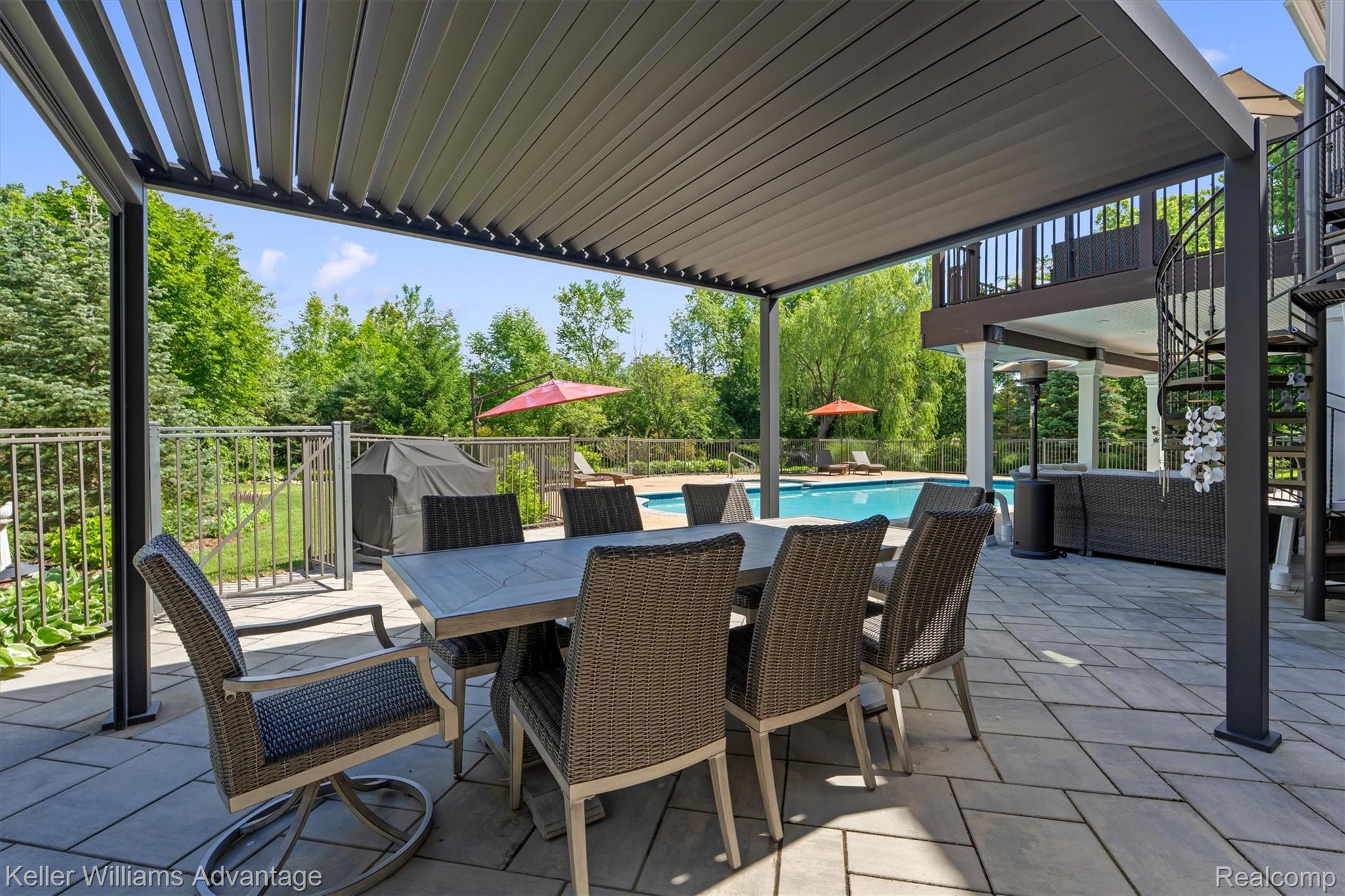 22878 Tree Top Court South Lyon, MI 48178 - Photo 54 of 75 Expansive paver patio featuring a louvered pergola, a heated pool, an outdoor kitchen area, a spiral staircase, and an upper-level balcony