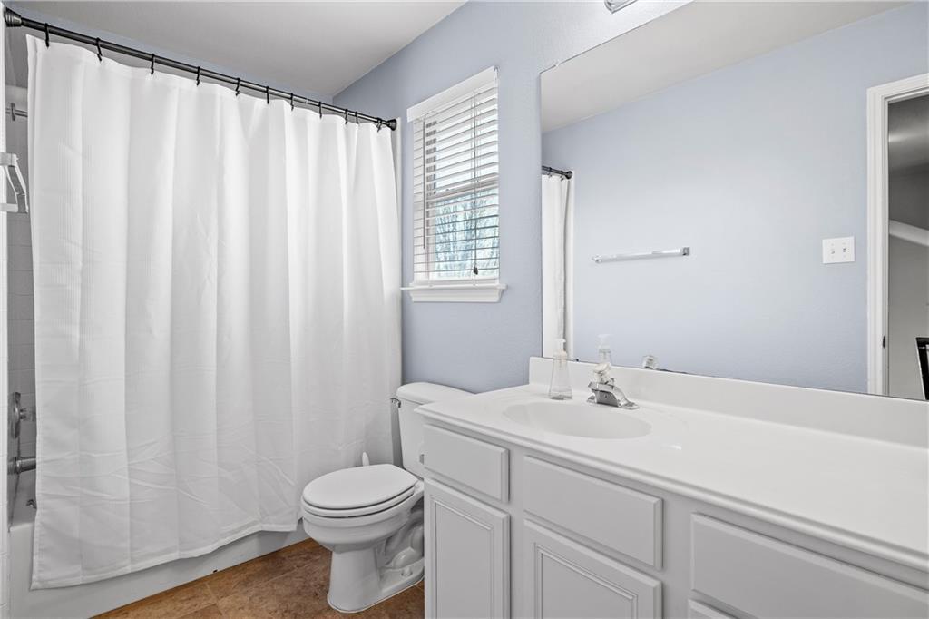 3508 Bratton Ridge Crossing Austin, TX 78728 - Photo 16 of 18 A pristine bathroom features a crisp white vanity, toilet, and bathtub with a shower curtain.