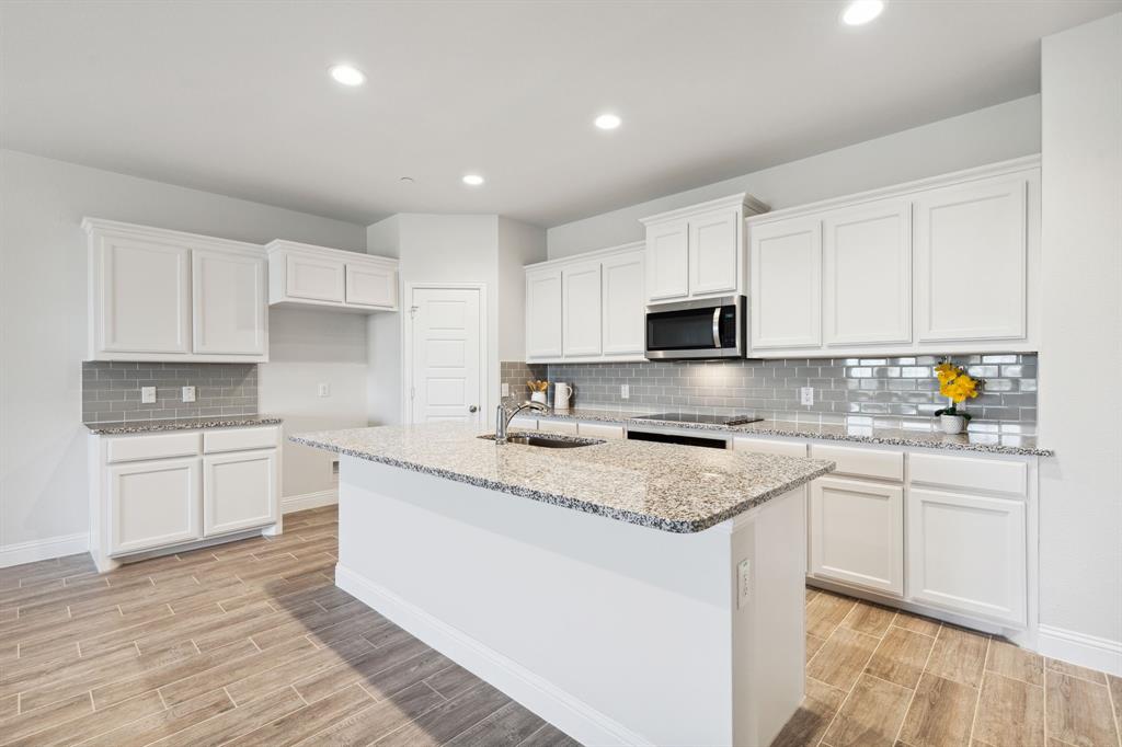 6028 Bursey Road Watauga, TX 76148 - Photo 9 of 27 a kitchen with granite countertop white cabinets sink and stainless steel appliances