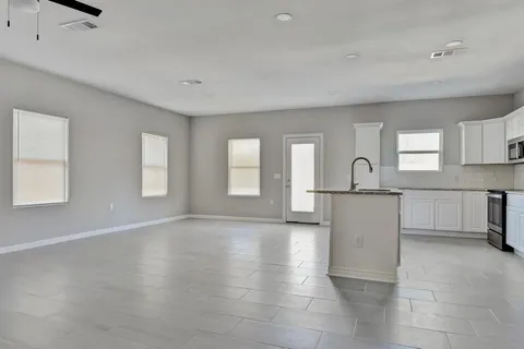 a view of empty room with kitchen and window