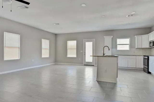 a view of empty room with kitchen and window