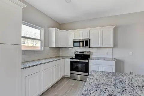 a kitchen with stainless steel appliances granite countertop a stove a sink and a microwave