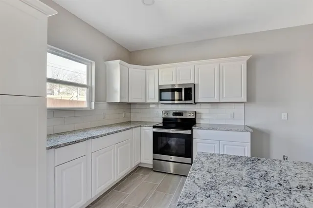 a kitchen with stainless steel appliances granite countertop a stove a sink and a microwave