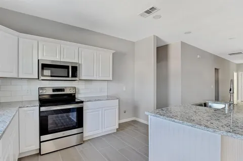 a kitchen with granite countertop white cabinets stainless steel appliances and a sink