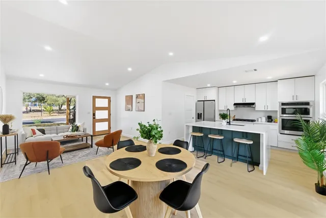 a view of kitchen with kitchen island stainless steel appliances sink stove dining table and chairs in it