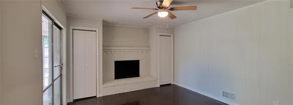 a view of an empty room with wooden floor and a fireplace