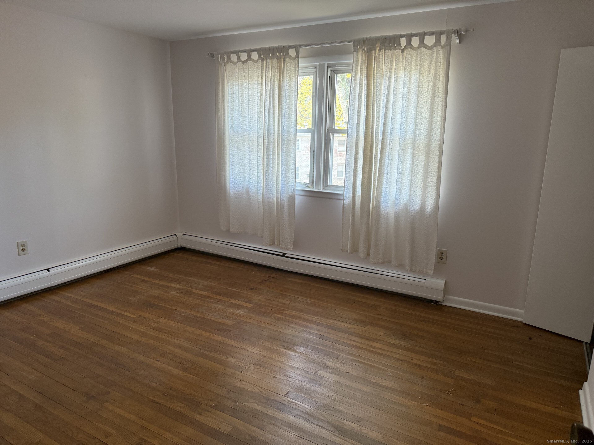 165 Yaremich Drive Bridgeport, CT 06606 - Photo 5 of 9 a view of an empty room with wooden floor and a window