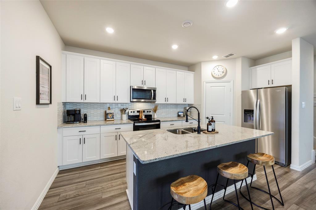 307 Quarry Street Melissa, TX 75454 - Photo 6 of 25 a kitchen with stainless steel appliances granite countertop a sink a stove a refrigerator a center island and cabinets