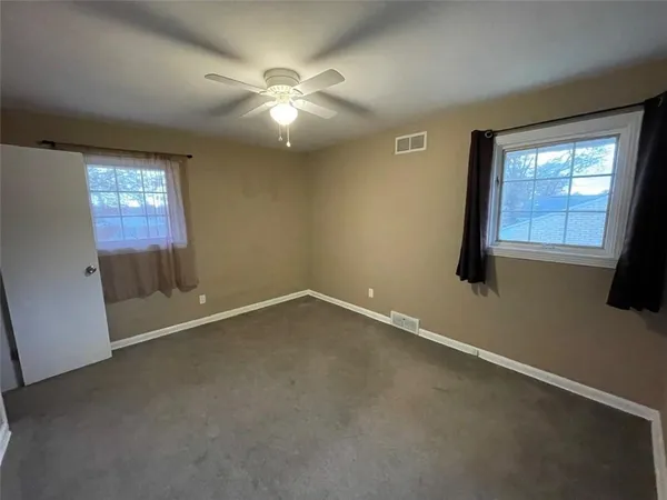 an empty room with windows and fan