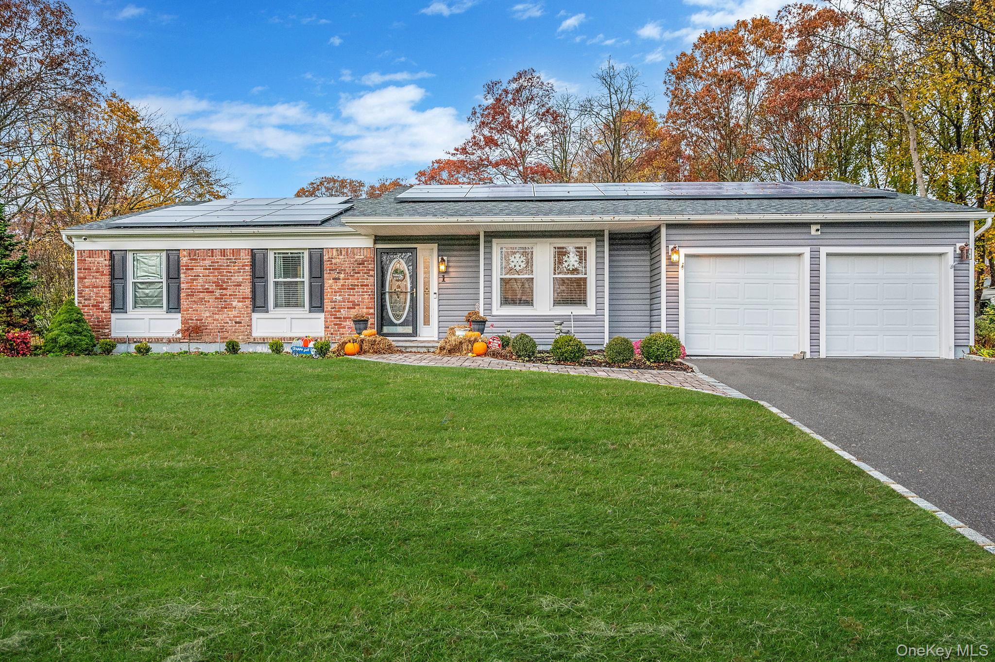 1 Fuller Drive Ridge, NY 11961 - Photo 1 of 1 View of front of home with a front lawn, driveway, solar panels, an attached garage, and brick siding