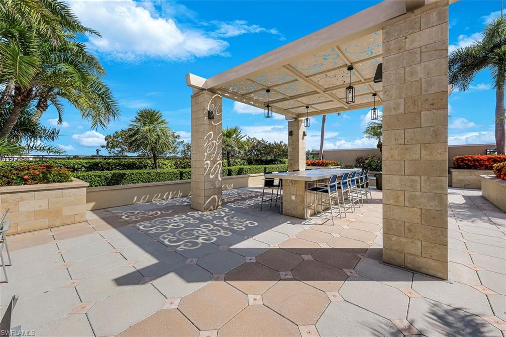 9123 Strada Place, Unit 7201 Naples, FL 34108 - Photo 32 of 50 a view of a patio with a table and chairs under an umbrella