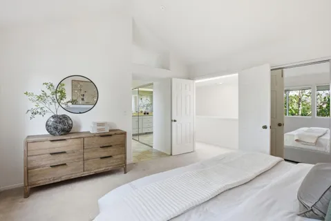 a bedroom with a bed a mirror on dresser and a window