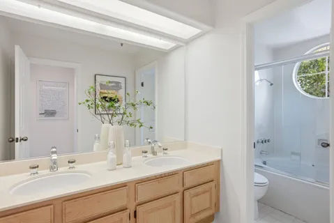 a bathroom with a granite countertop sink a toilet a shower and a mirror