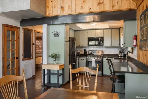 a kitchen with a stove a refrigerator and a dining table with wooden floor