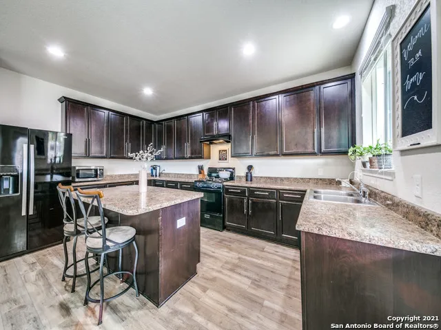 a kitchen with stainless steel appliances granite countertop a sink stove refrigerator and cabinets