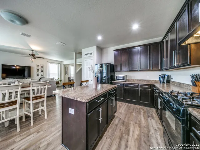 a kitchen with stainless steel appliances granite countertop a stove top oven a sink dishwasher a dining table and chairs with wooden floor