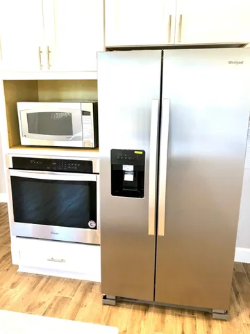 a view of an empty room with window and a kitchen