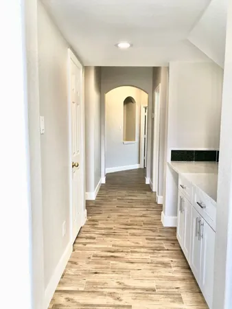 a view of empty room with wooden floor and fan
