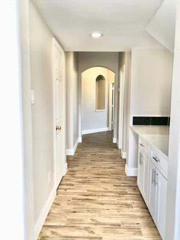 a view of empty room with wooden floor and fan