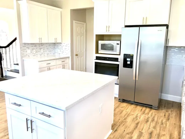 a kitchen with kitchen island a counter top space a refrigerator and a sink